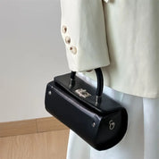 Giacca bianca elegante con borsa a mano nera in pelle, design moderno, chiusura metallica, moda donna, accessorio di lusso, stile minimalista.