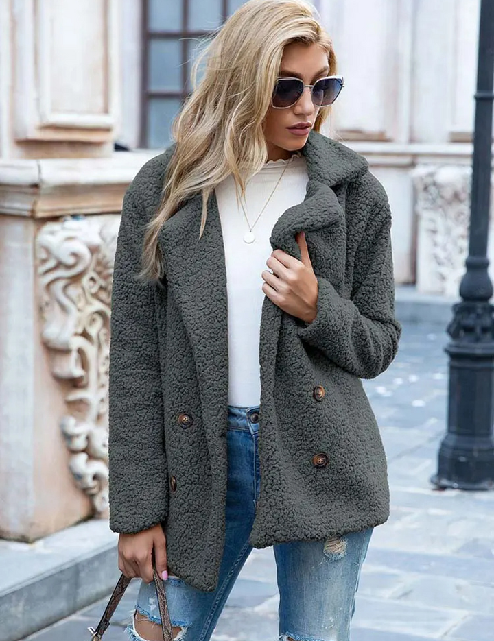 Donna con cappotto in pile grigio, jeans strappati e occhiali da sole, passeggia in città. Moda autunnale, abbigliamento casual elegante.