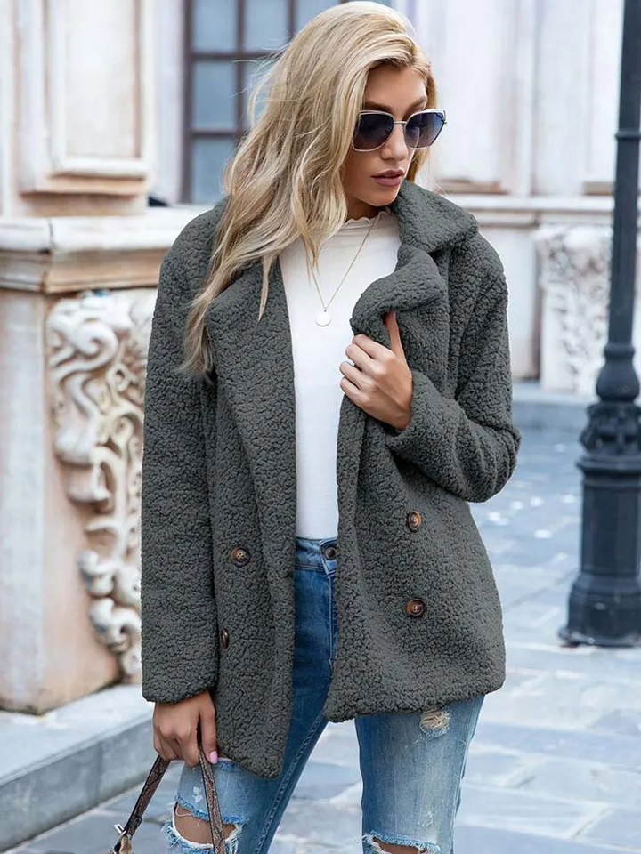 Donna con cappotto in pile grigio, jeans strappati e occhiali da sole, passeggia in città. Moda autunnale, abbigliamento casual elegante.