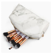 Set di pennelli trucco con manici dorati in pochette effetto marmo bianco. Accessori cosmetici eleganti per make-up professionale.