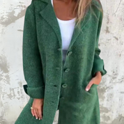Cappotto verde donna, elegante e lungo, con bottoni e tasche, indossato su maglia bianca. Moda autunnale, stile casual chic.