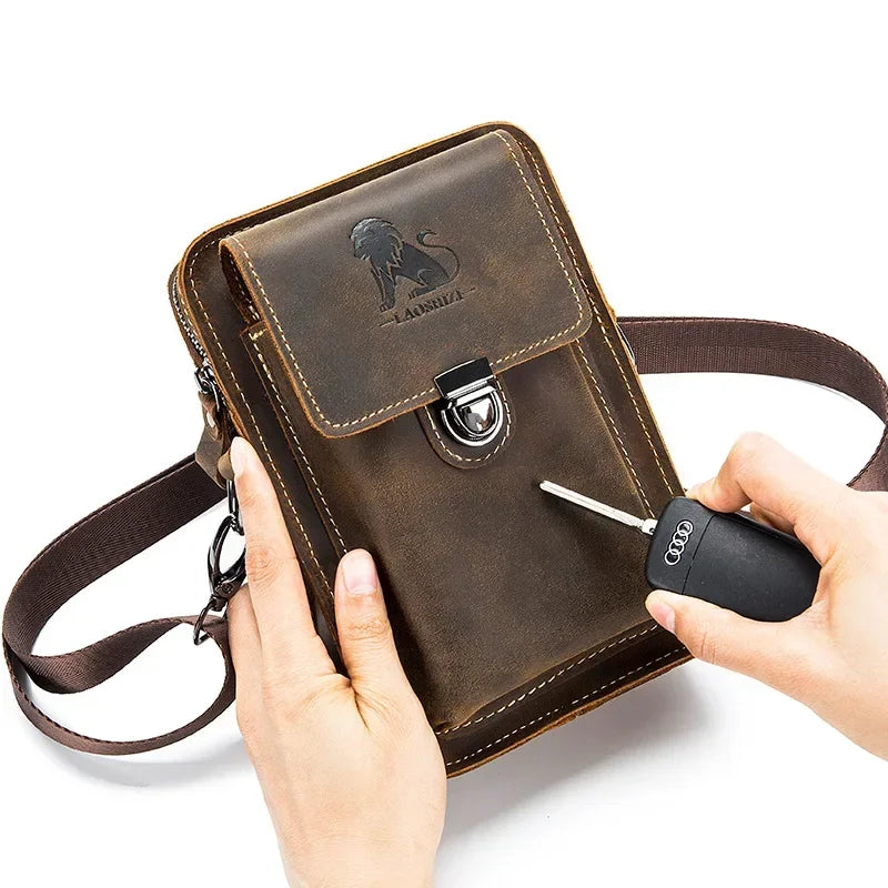 Borsa a tracolla in pelle marrone con chiusura a fibbia, logo inciso, e tasca frontale. Mani che tengono chiave auto. Accessorio moda uomo elegante.