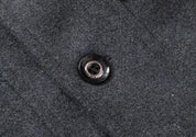 Pulsante nero su tessuto grigio in lana, dettaglio moda abbigliamento invernale, texture elegante e raffinata, ideale per cappotti e giacche.