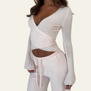 Top bianco a maniche lunghe con scollo a V profondo e pantaloni coordinati, abbigliamento donna elegante, moda casual, tessuto morbido.