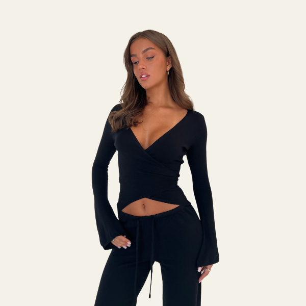 Maglia nera a maniche lunghe con scollo a V e dettaglio incrociato, indossata da una donna. Abbigliamento moda donna elegante e moderno.