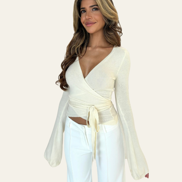 Donna con maglia incrociata bianca a maniche lunghe e pantaloni bianchi. Moda femminile elegante, abbigliamento casual chic, tendenze 2023.