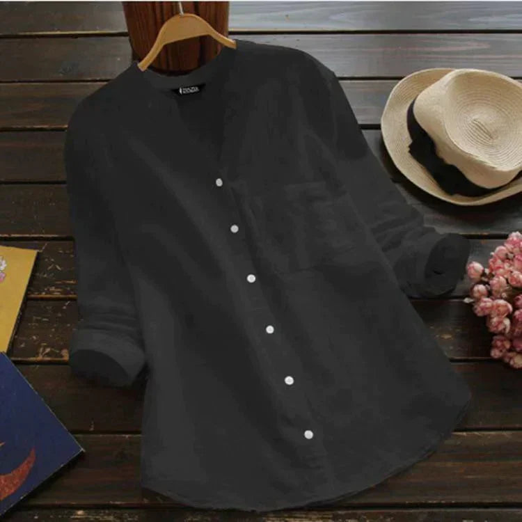 Camicia nera da donna in cotone, maniche lunghe, colletto alla coreana, bottoni bianchi, stile casual, su sfondo di legno con cappello e fiori.
