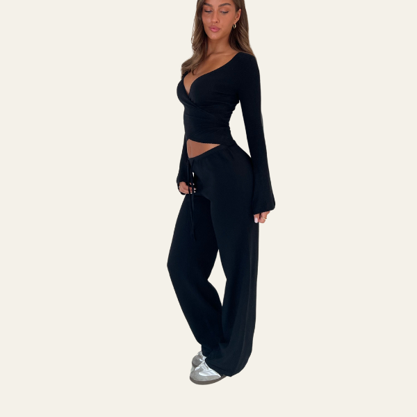 Donna in abbigliamento nero elegante, top a maniche lunghe e pantaloni larghi, indossa scarpe sportive. Moda casual chic, abbigliamento femminile moderno.