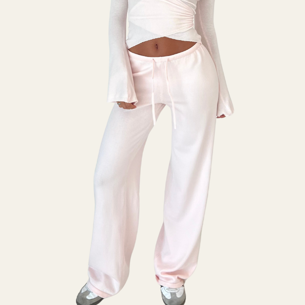 Pantaloni larghi rosa chiaro da donna, vita alta con laccio, abbinati a top bianco a maniche lunghe. Stile casual, moda femminile.