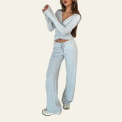 Donna in abbigliamento casual: set coordinato grigio con felpa a maniche lunghe e pantaloni larghi. Stile comodo e moderno, perfetto per il tempo libero.