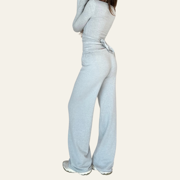 Donna in tuta grigia, pantaloni larghi e maglia a maniche lunghe, scarpe da ginnastica bianche. Abbigliamento casual, moda donna, comfort.