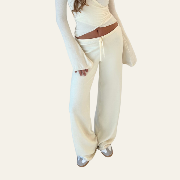 Pantaloni larghi bianchi da donna, vita alta, tessuto morbido, abbinati a top bianco a maniche lunghe. Stile casual elegante, moda femminile.