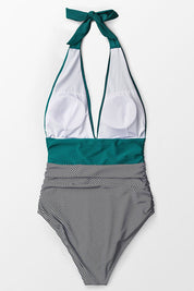 Costume intero donna a righe bianche e nere, scollo profondo, con dettagli verde acqua. Elegante e alla moda per l'estate.