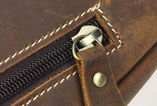 Cerniera in metallo su borsa in pelle marrone, cuciture bianche a contrasto, dettaglio artigianale, accessorio moda elegante e resistente.
