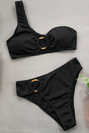 Costume da bagno bikini nero a un solo spallino con dettagli ad anello. Design elegante e moderno, perfetto per la moda mare estiva.