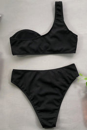 Costume da bagno nero donna, bikini asimmetrico a vita alta, design moderno ed elegante, perfetto per l'estate e la spiaggia.