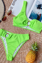 Bikini verde fluo a costine con anello decorativo su sfondo estivo, ananas, occhiali da sole e rivista. Moda mare, costumi da bagno trendy.