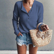 Donna con maglia blu a maniche lunghe, jeans corti e borsa di paglia intrecciata. Moda casual estiva, abbigliamento femminile trendy.