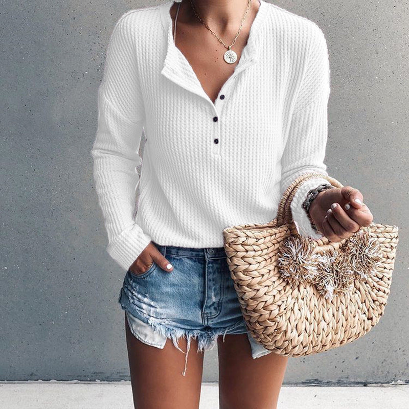 Donna con maglione bianco a coste, shorts di jeans e borsa di paglia intrecciata. Moda casual estiva, abbigliamento femminile trendy.