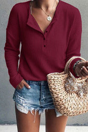 Donna con maglione rosso a coste, shorts di jeans strappati e borsa di paglia intrecciata. Moda casual estiva, abbigliamento femminile trendy.