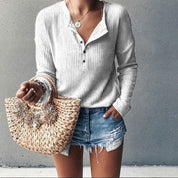 Donna con maglione bianco a coste, shorts di jeans strappati e borsa di paglia intrecciata. Moda casual estiva, abbigliamento femminile trendy.
