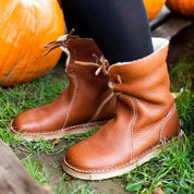 Stivali in pelle marrone su erba verde, design casual con cuciture bianche, perfetti per l'autunno. Scarpe comode e alla moda per donna.