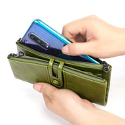 Mani inseriscono smartphone in portafoglio verde in pelle con cerniera. Accessorio moda, pratico per organizzare carte e contanti.