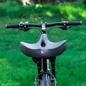 Sella bici ergonomica nera su bici da montagna, manubrio con impugnature rosse, sfondo verde. Accessori ciclismo, comfort, outdoor.