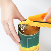Apriscatole giallo in uso su lattina di metallo verde con frutta. Utensile da cucina pratico per aprire facilmente barattoli. Accessorio essenziale.