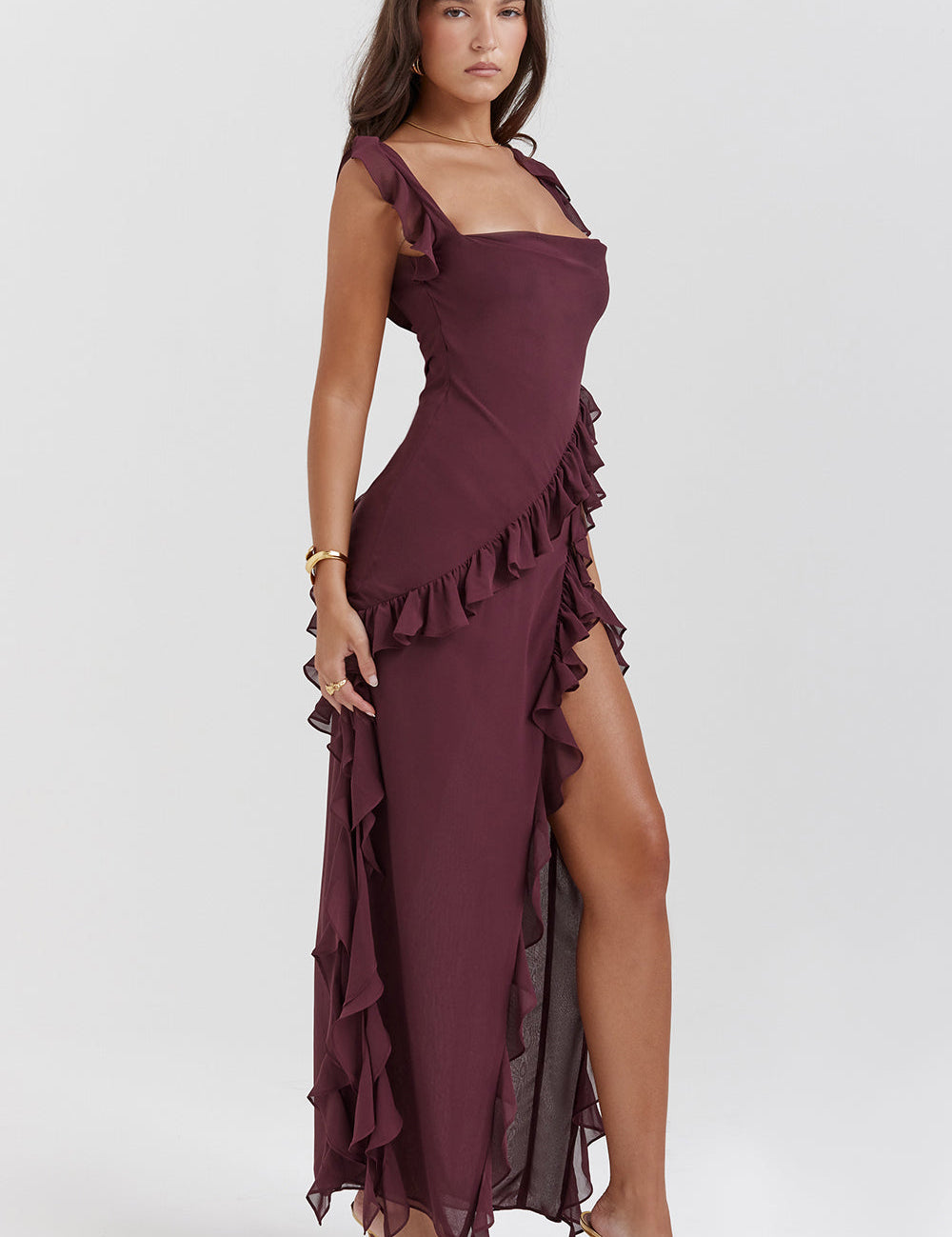 Abito lungo elegante bordeaux con volant, spacco laterale e spalline sottili. Perfetto per eventi serali e cerimonie. Moda donna sofisticata.