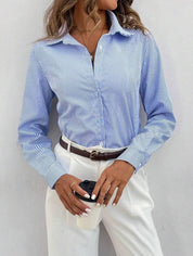 Donna con camicia a righe blu e pantaloni bianchi, tiene una tazza da caffè. Look elegante e casual, moda femminile, abbigliamento da ufficio.