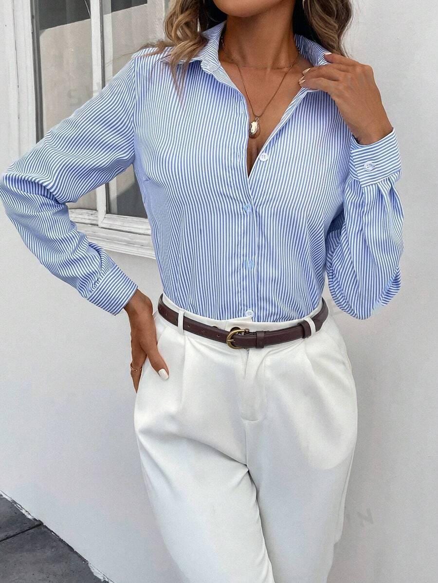 Camicia a righe blu e bianche da donna, abbinata a pantaloni bianchi eleganti. Look casual chic, perfetto per l'ufficio o eventi formali.