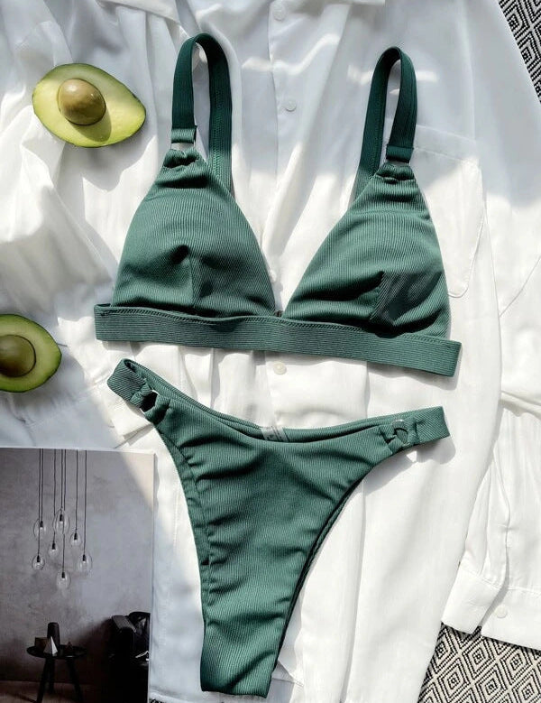 Bikini verde a costine su camicia bianca, con avocado tagliato a metà. Moda mare donna, costumi da bagno estivi, tendenze beachwear 2023.
