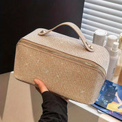 Borsa cosmetica beige con manico, tessuto scintillante, chiusura a zip, ideale per organizzare trucchi e accessori. Design elegante e pratico.