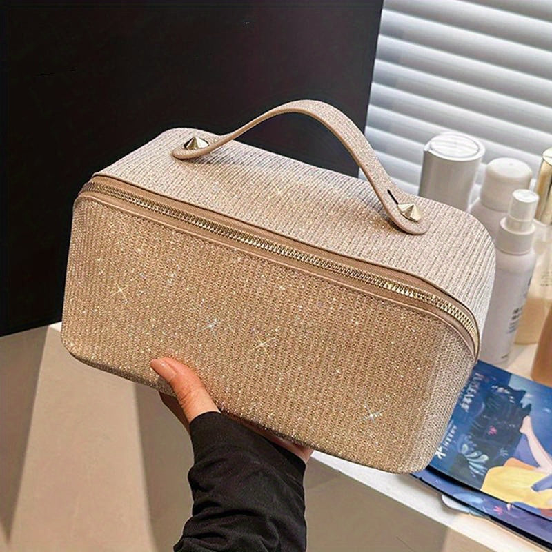 Borsa cosmetica beige con manico, tessuto scintillante, chiusura a zip, ideale per organizzare trucchi e accessori. Design elegante e pratico.