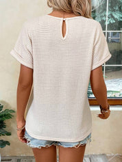 Donna con maglia bianca a maniche corte e shorts di jeans strappati, vista posteriore. Stile casual estivo, moda femminile trendy.