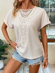 Maglietta beige in pizzo traforato, maniche corte, abbinata a shorts di jeans. Look estivo casual per donna. Moda femminile trendy.