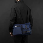 Borsa a tracolla blu scuro per laptop, design elegante e moderno, indossata da una persona in abbigliamento nero. Accessorio moda funzionale.
