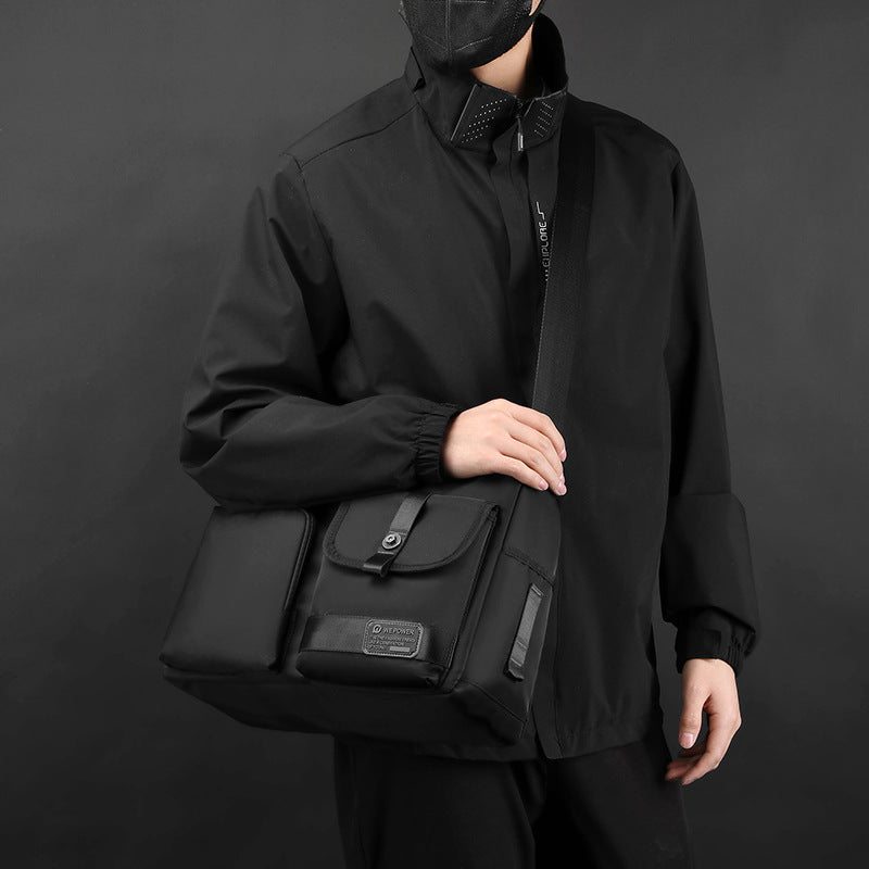 Uomo con giacca nera indossa borsa a tracolla nera elegante, tasche multiple, design moderno. Accessorio moda maschile, stile urbano.