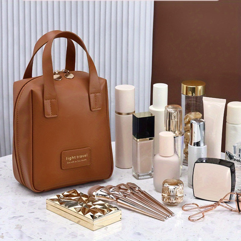 Borsa da viaggio marrone in pelle sintetica con zip, circondata da cosmetici e accessori su tavolo di marmo. Elegante e pratica per organizzare il trucco.