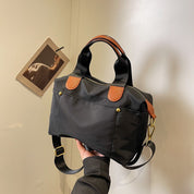 Borsa a mano nera in nylon con dettagli in pelle marrone, tracolla regolabile, design elegante e moderno, perfetta per uso quotidiano.