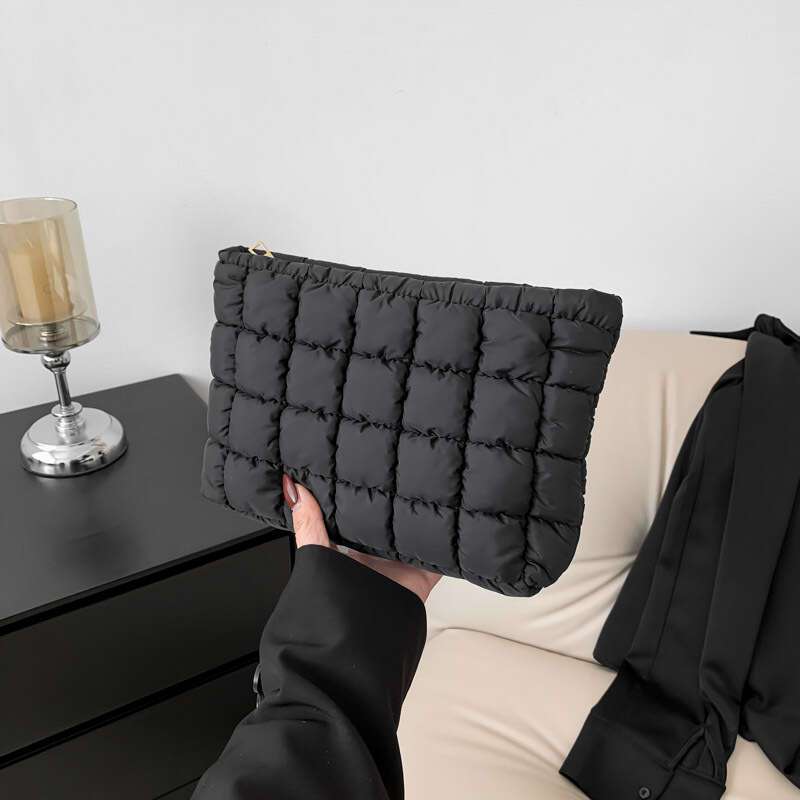 Borsa a mano trapuntata nera su sfondo moderno, elegante e versatile. Accessorio moda donna, perfetto per ogni occasione.