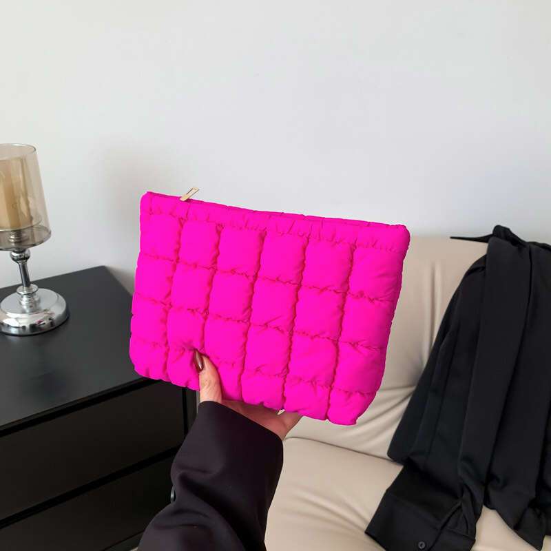 Borsa clutch trapuntata fucsia, design moderno, tenuta in mano. Accessorio moda elegante, ideale per eventi serali. Sfondo neutro.