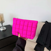 Borsa clutch trapuntata fucsia, design moderno, tenuta in mano. Accessorio moda elegante, ideale per eventi serali. Sfondo neutro.