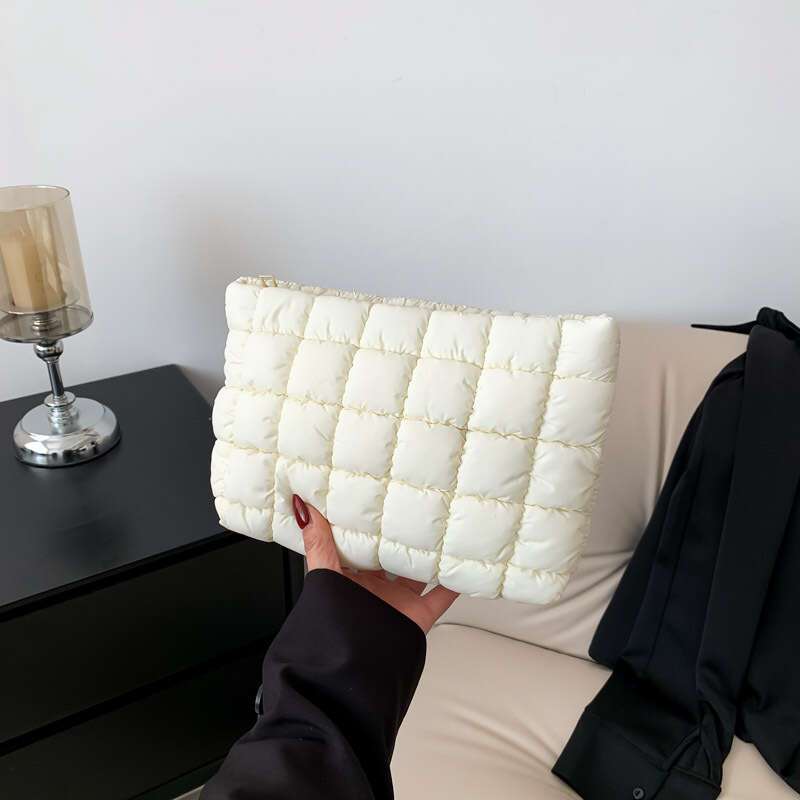 Borsa trapuntata bianca su divano beige, design elegante e moderno. Accessorio moda donna, perfetto per look casual e sofisticati.