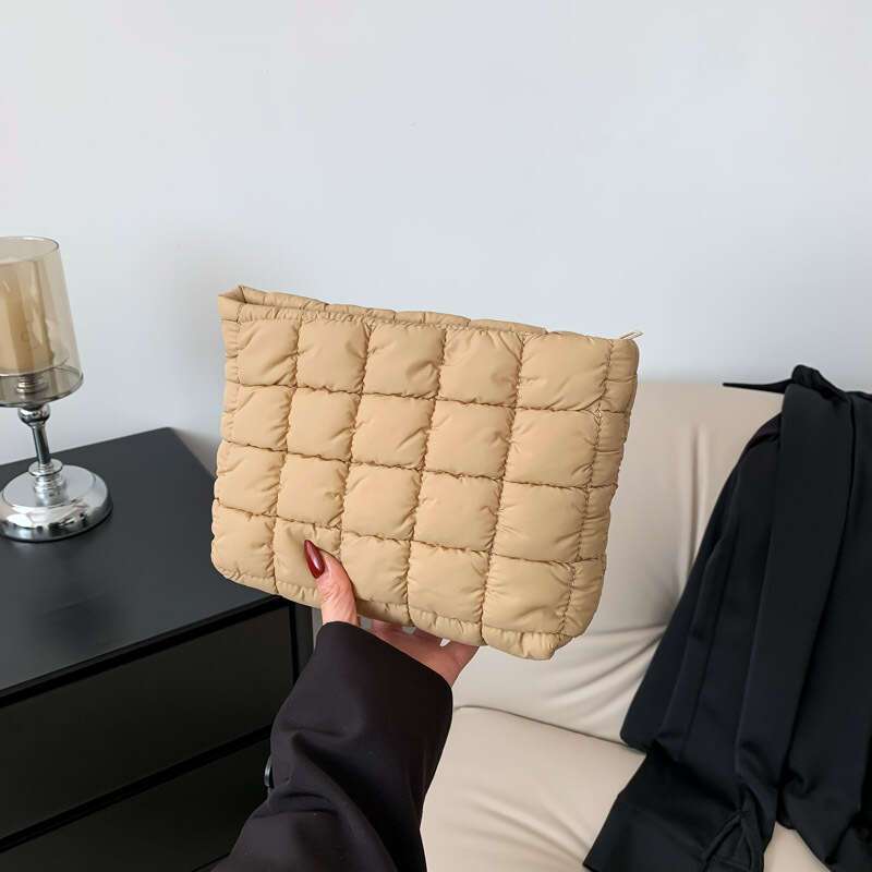 Borsa trapuntata beige su divano, design moderno. Accessorio moda donna, elegante e versatile. Perfetta per look casual e chic.
