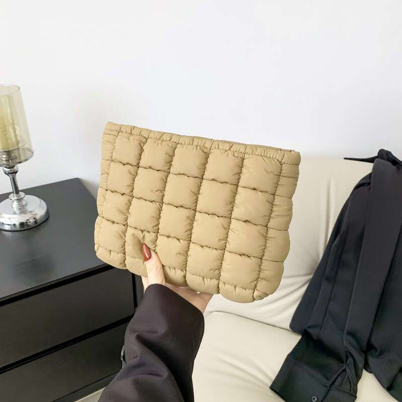 Borsa trapuntata beige tenuta in mano, design moderno e minimalista, ideale per moda autunno inverno. Accessorio elegante per donna.