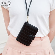 Portafoglio nero in pelle con texture coccodrillo, protezione RFID, indossato a tracolla su una persona in maglietta bianca e gonna rosa.
