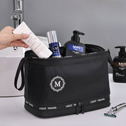Borsa da toilette nera con prodotti per la cura della pelle maschile, inclusi crema, lozione e rasoio, su lavandino moderno. Accessori da viaggio uomo.
