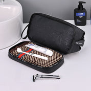 Nécessaire da viaggio nero con spazzolino, dentifricio e rasoio su asciugamano marrone. Accessori bagno eleganti e pratici per uomo.